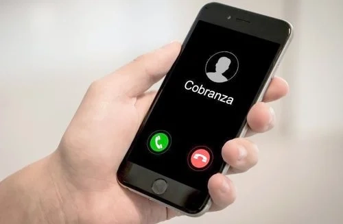 Persona recibiendo una llamada telefónica de acoso de un despacho de cobranza en México.